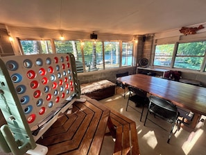 A room with a large wooden table, a seating bench, and a dartboard.