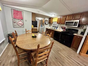 A compact kitchen with wooden cabinets, a microwave, and a stove.