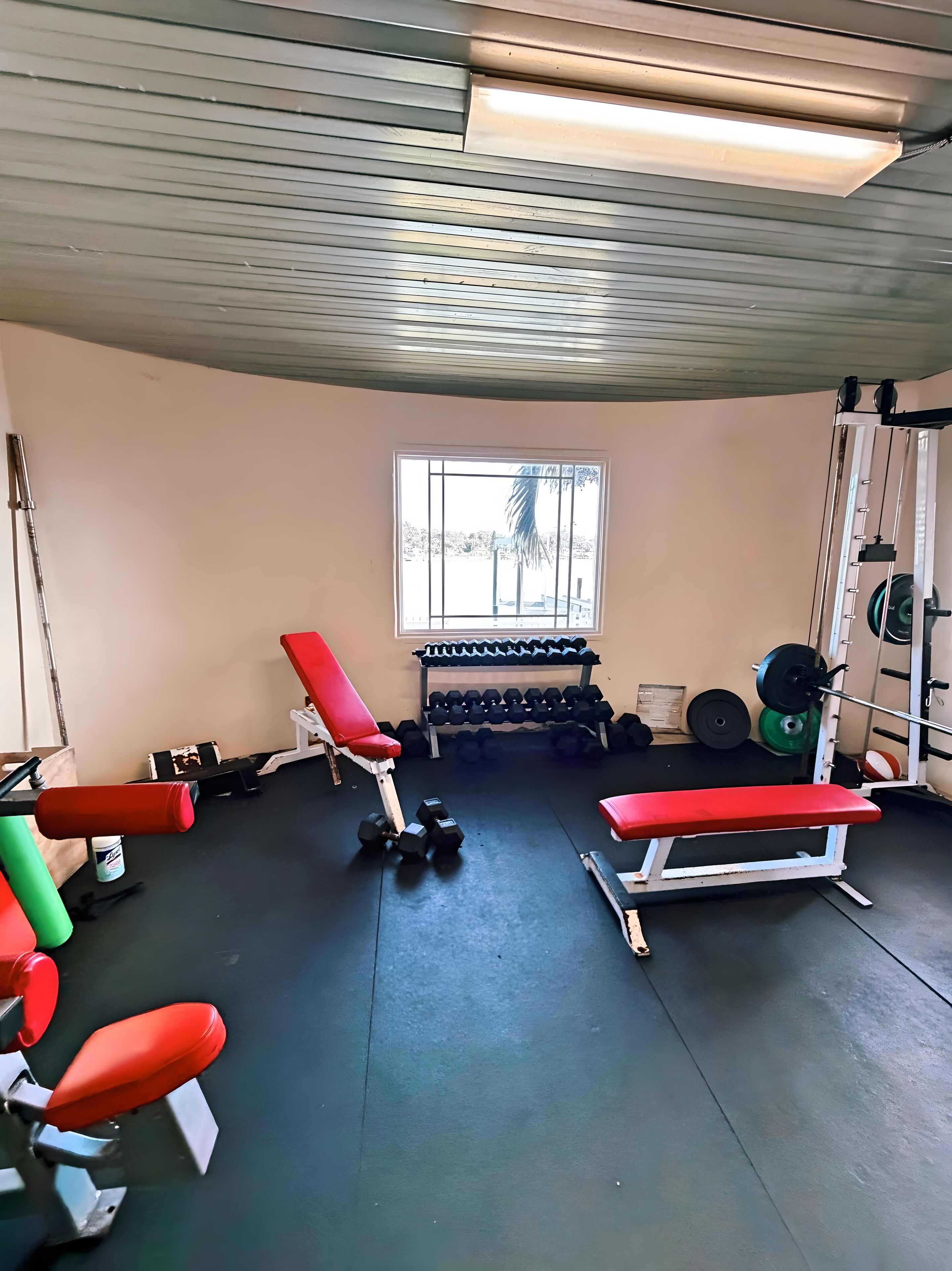 Un gimnasio con bancos, mancuernas y equipamiento para levantar pesas.
