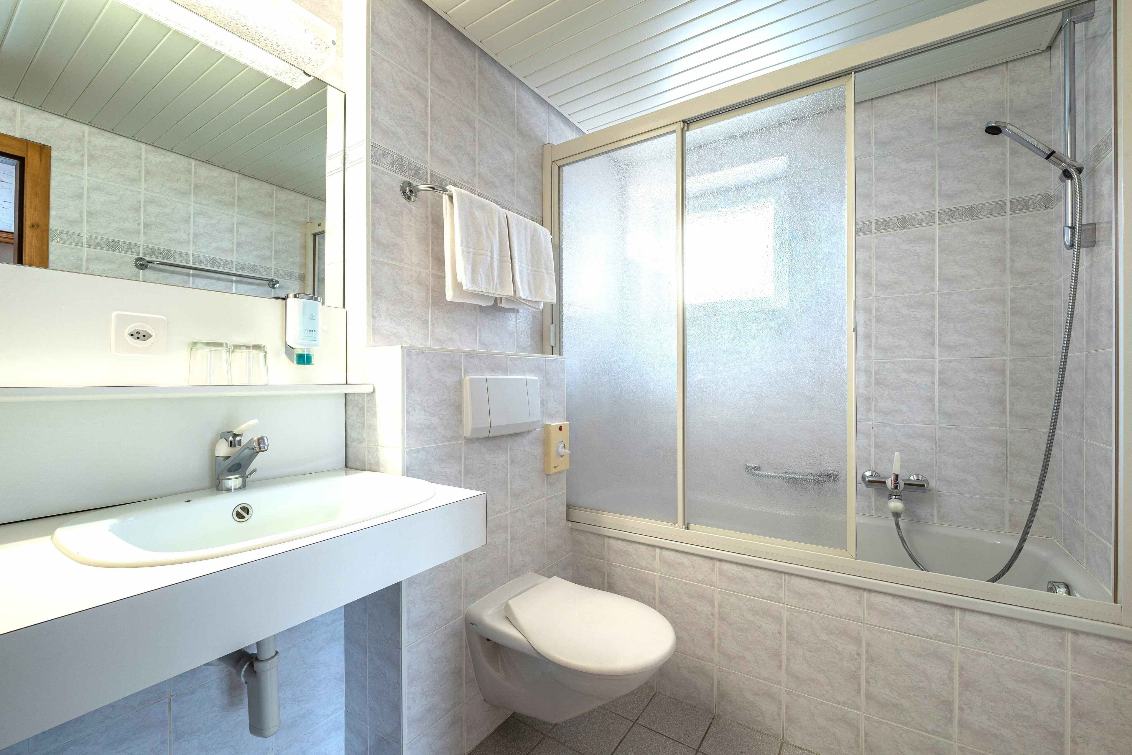 A modern bathroom with a white sink, a toilet, and a glass-enclosed shower.
