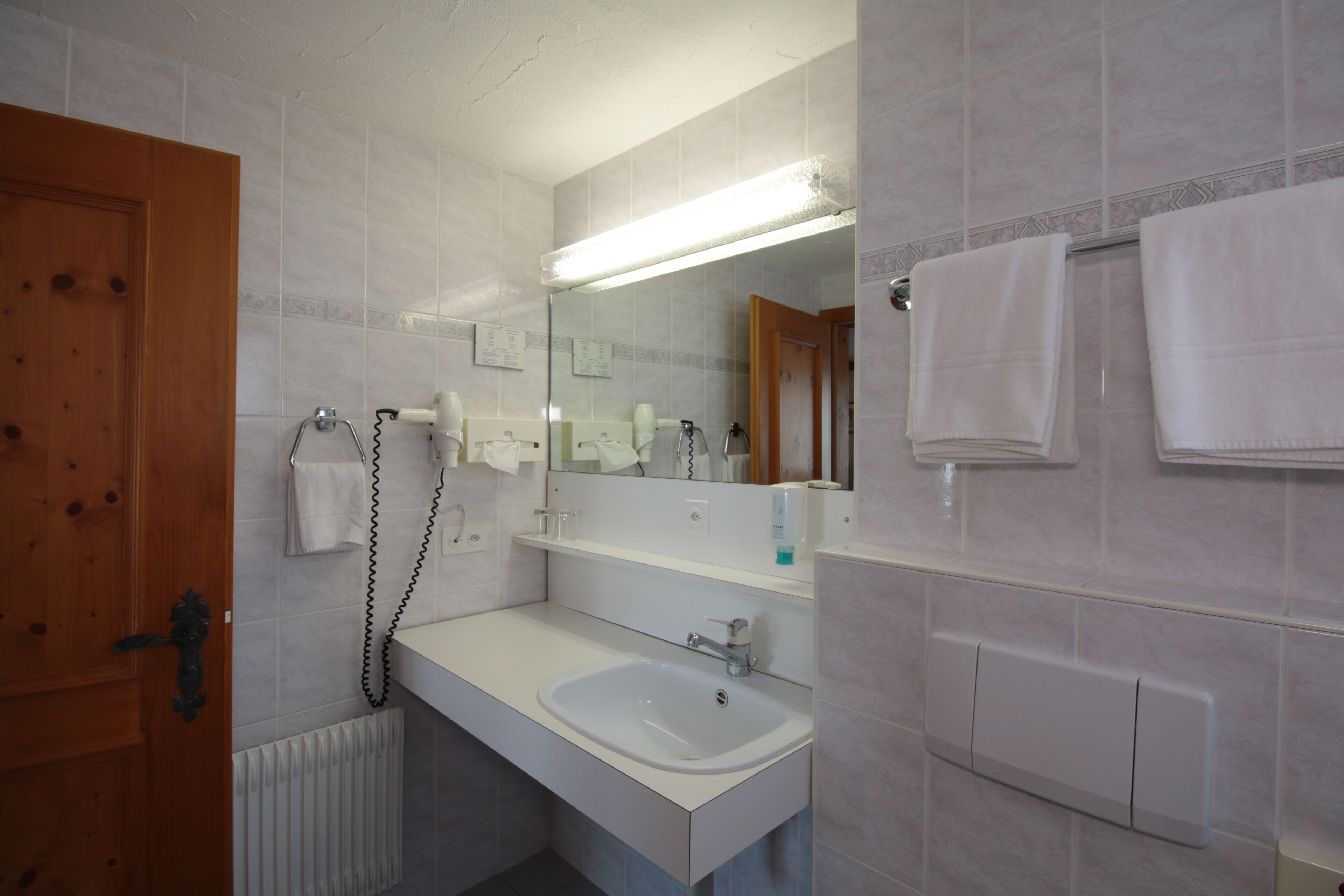 Casa de banho com lavatório branco, espelho e porta-toalhas.