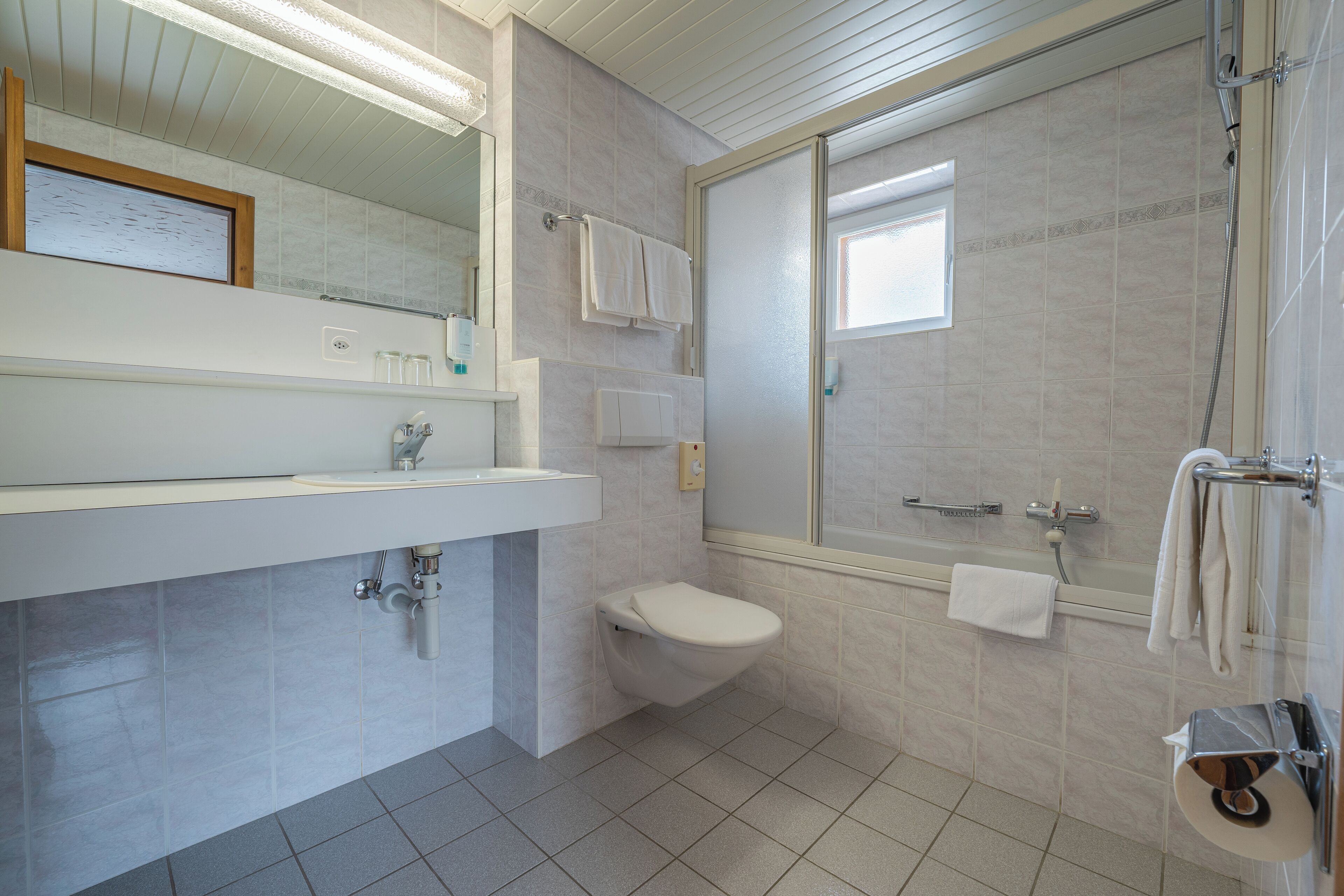A modern bathroom with a toilet, sink, and shower.