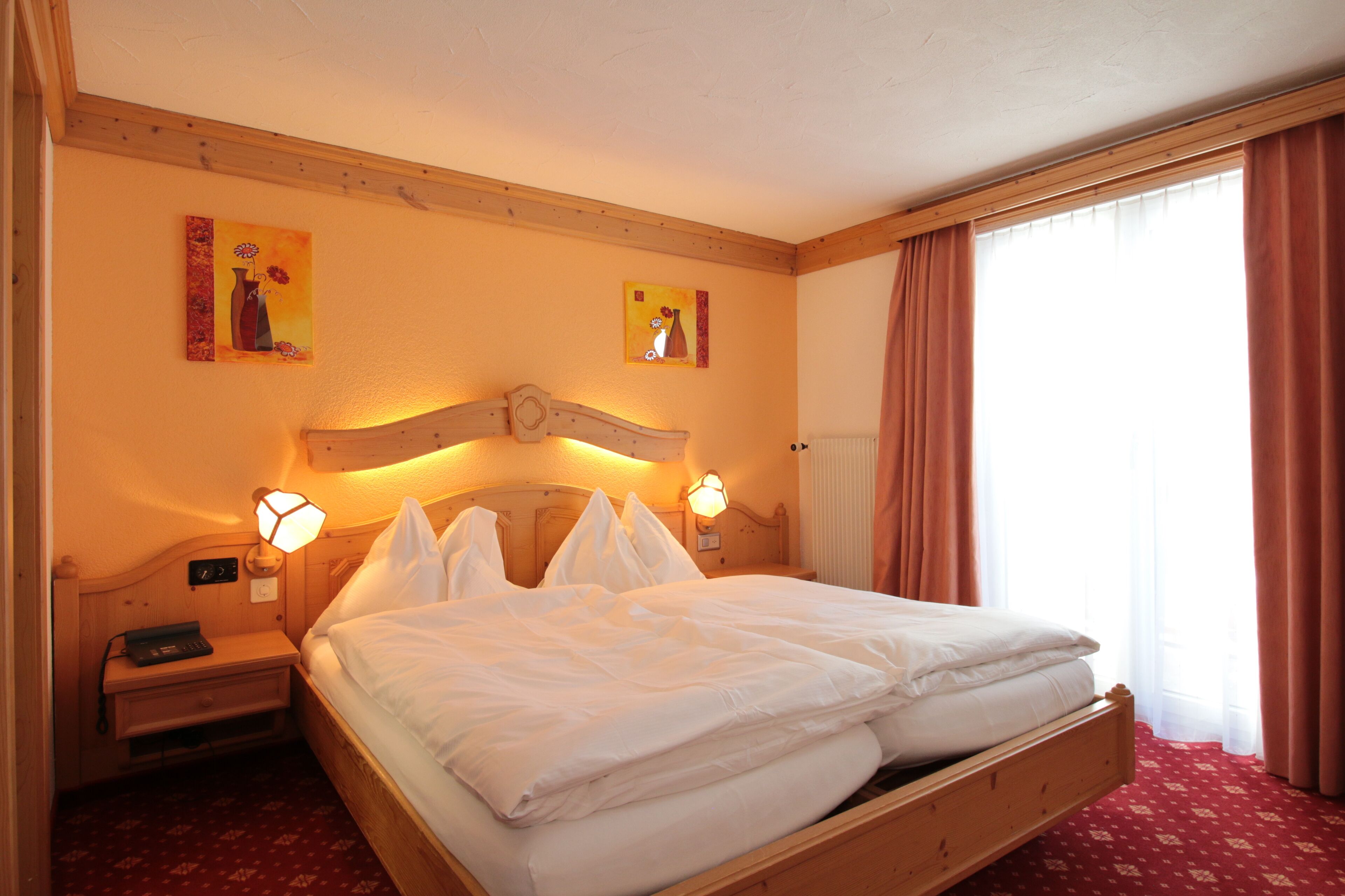 A neatly made bed with white linens, a wooden headboard, and two bedside lamps.