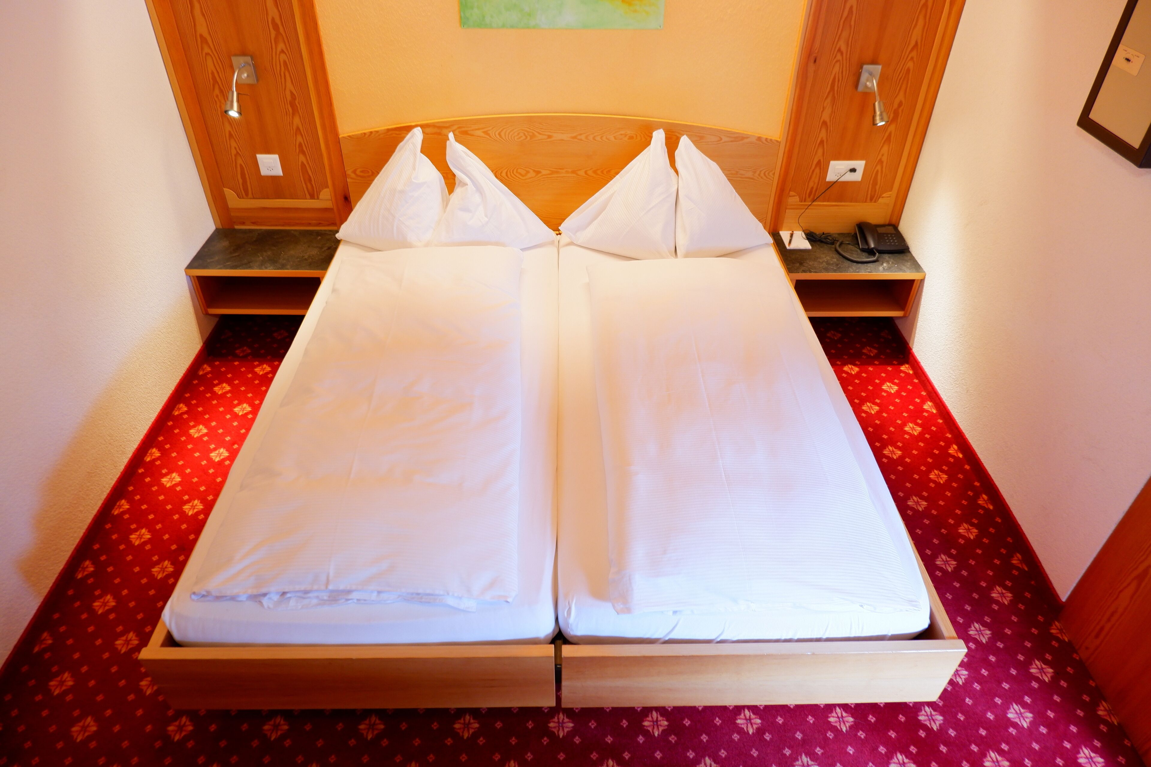 Ein Doppelbett mit weißen Bettwäsche in einem Zimmer mit Holz-Kopfstück und Nachttischen.