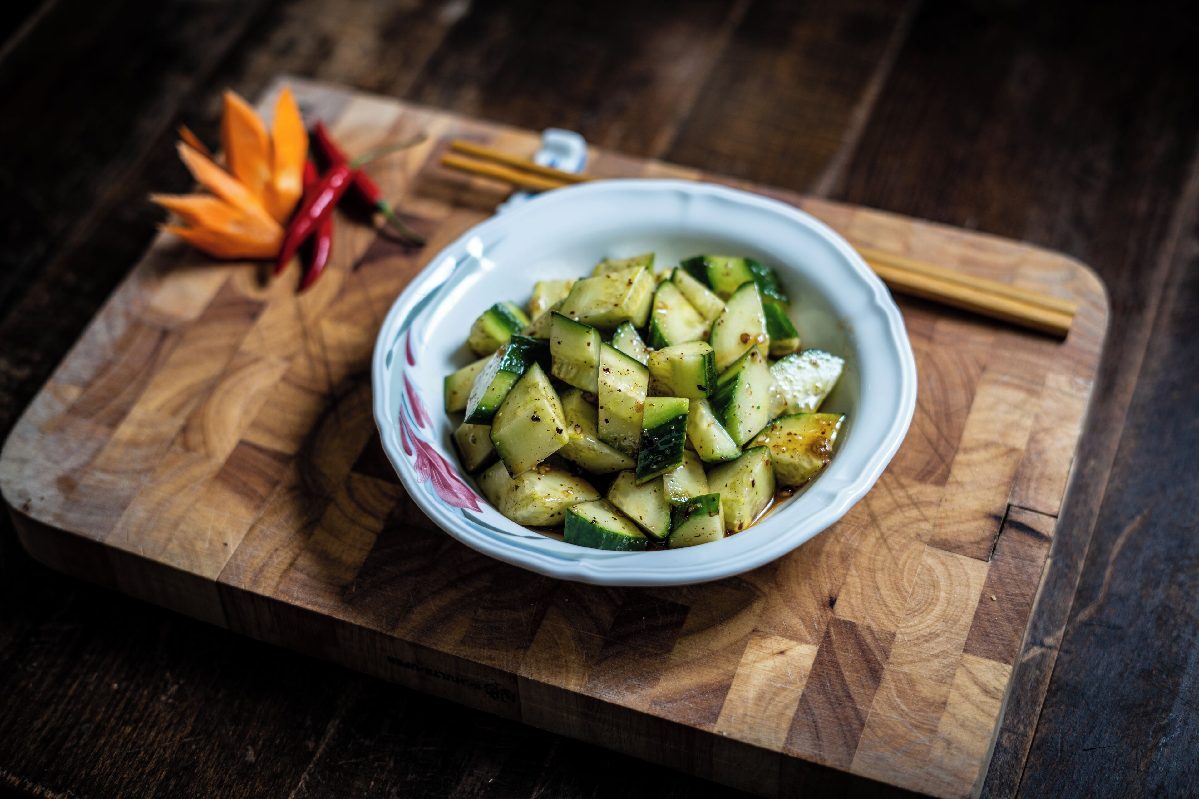 A bowl of seasoned zucchini on a wooden cutting board.