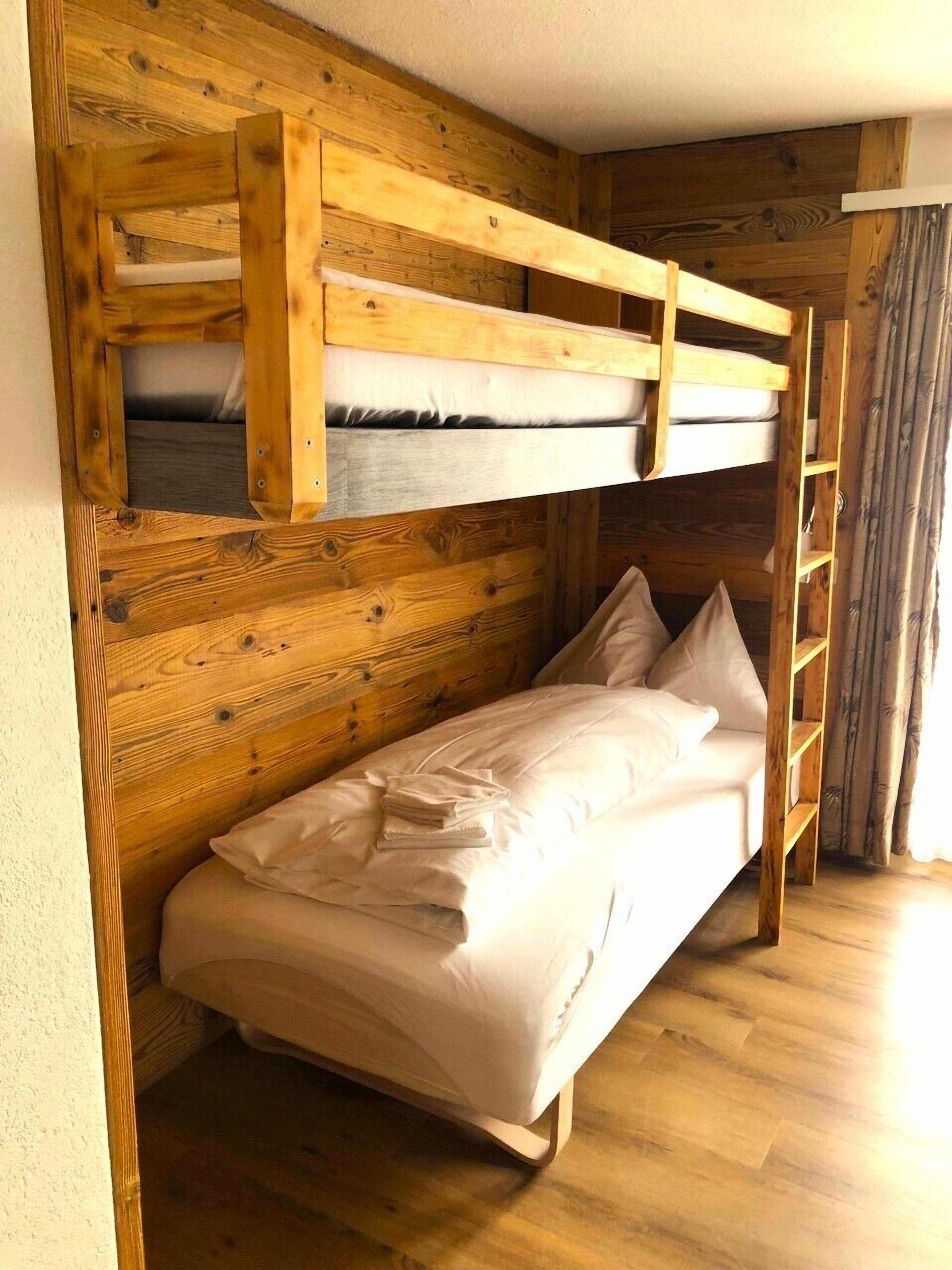 A bunk bed with a wooden headboard and a single bed below.