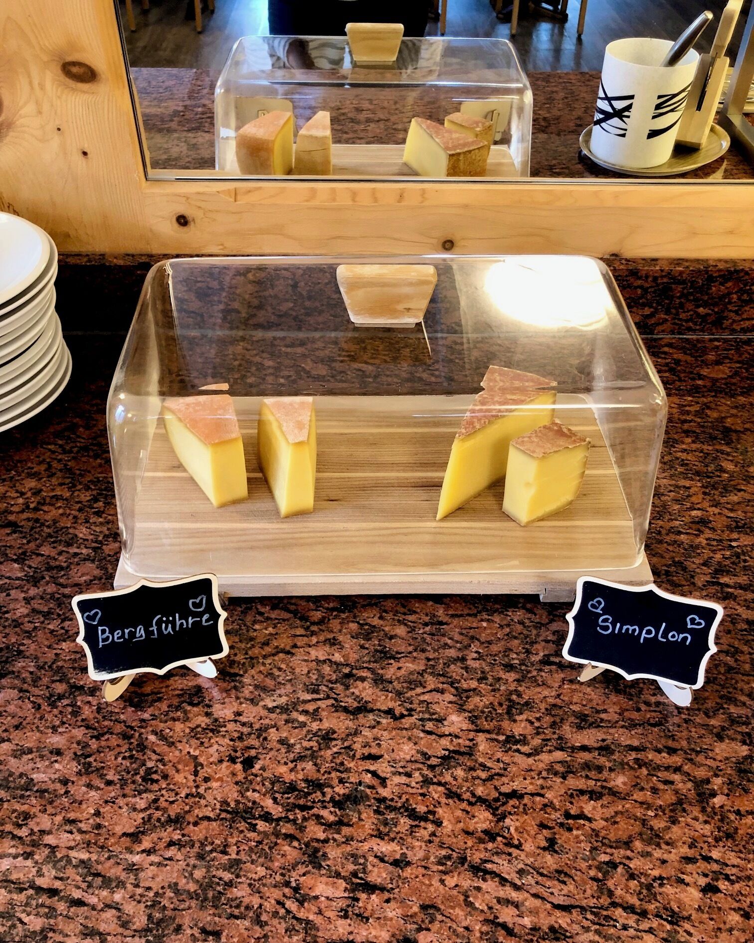 A display of cheese with labels 'Bergführe' and 'Simplon' on a granite countertop.