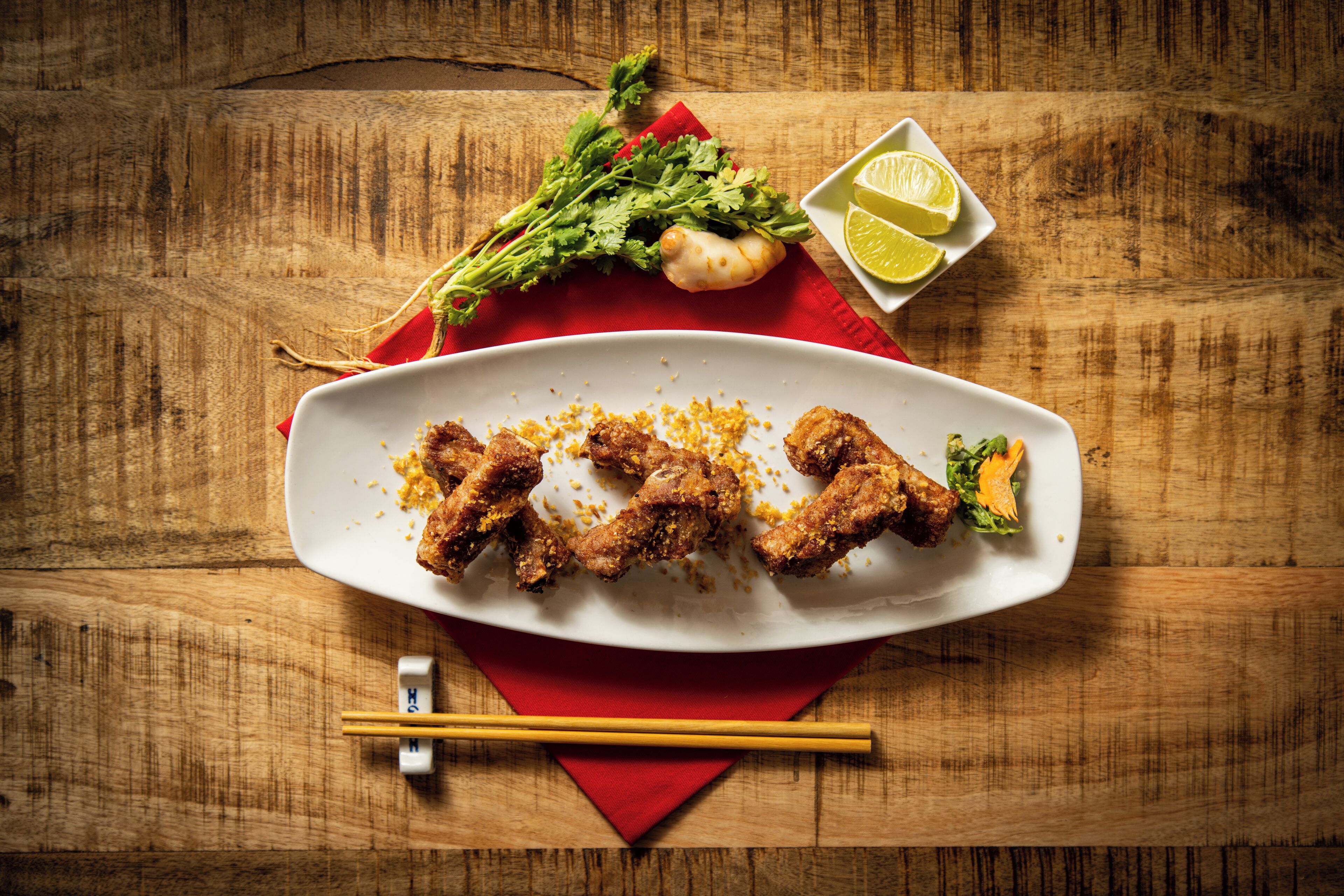 Un plato blanco con pollo frito sobre una mesa de madera.