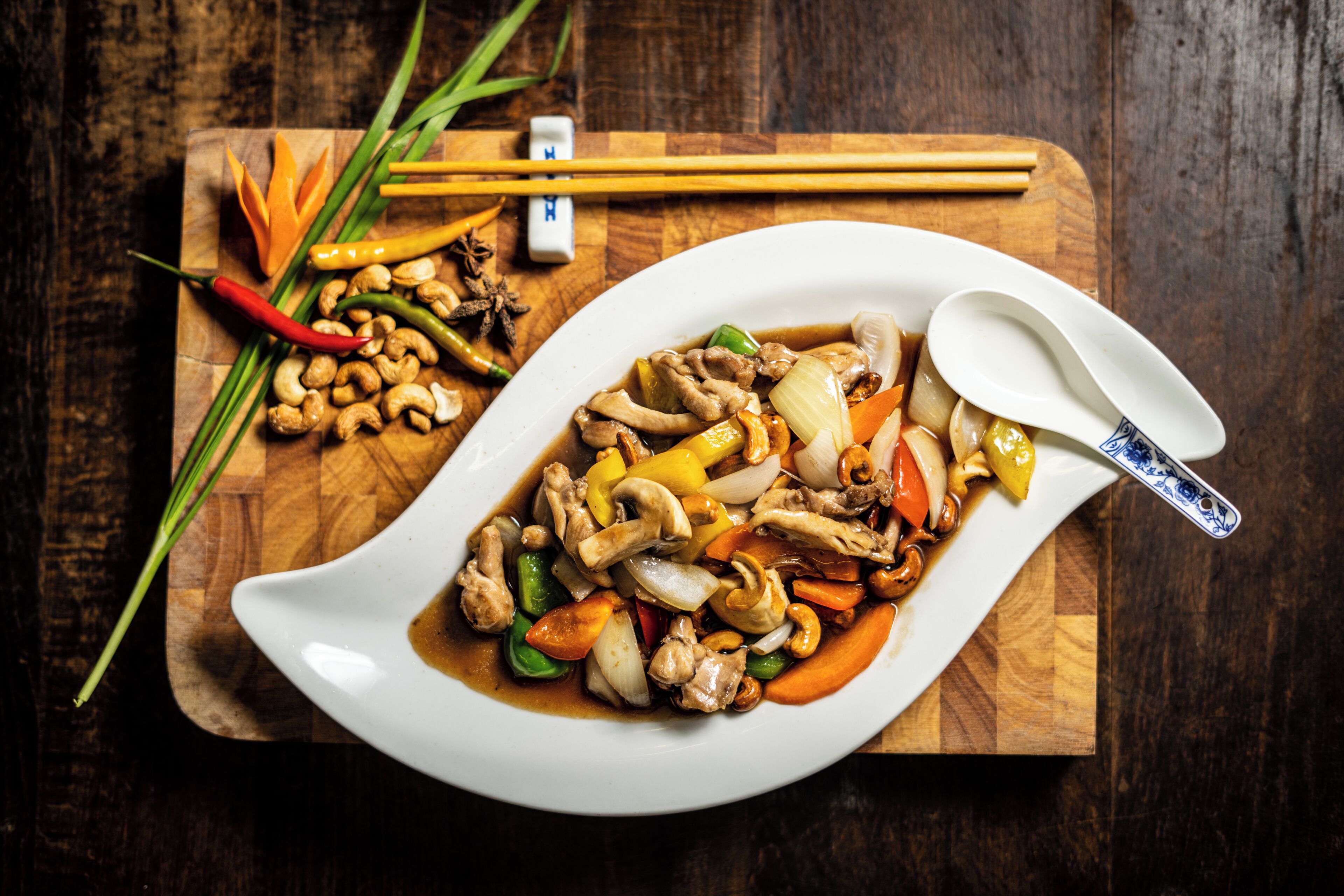 Une assiette blanche contenant un plat de légumes sautés, le tout posé sur une planche en bois.