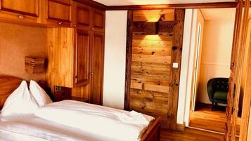 A bedroom with a wooden bed, a stone wall, and a green chair.