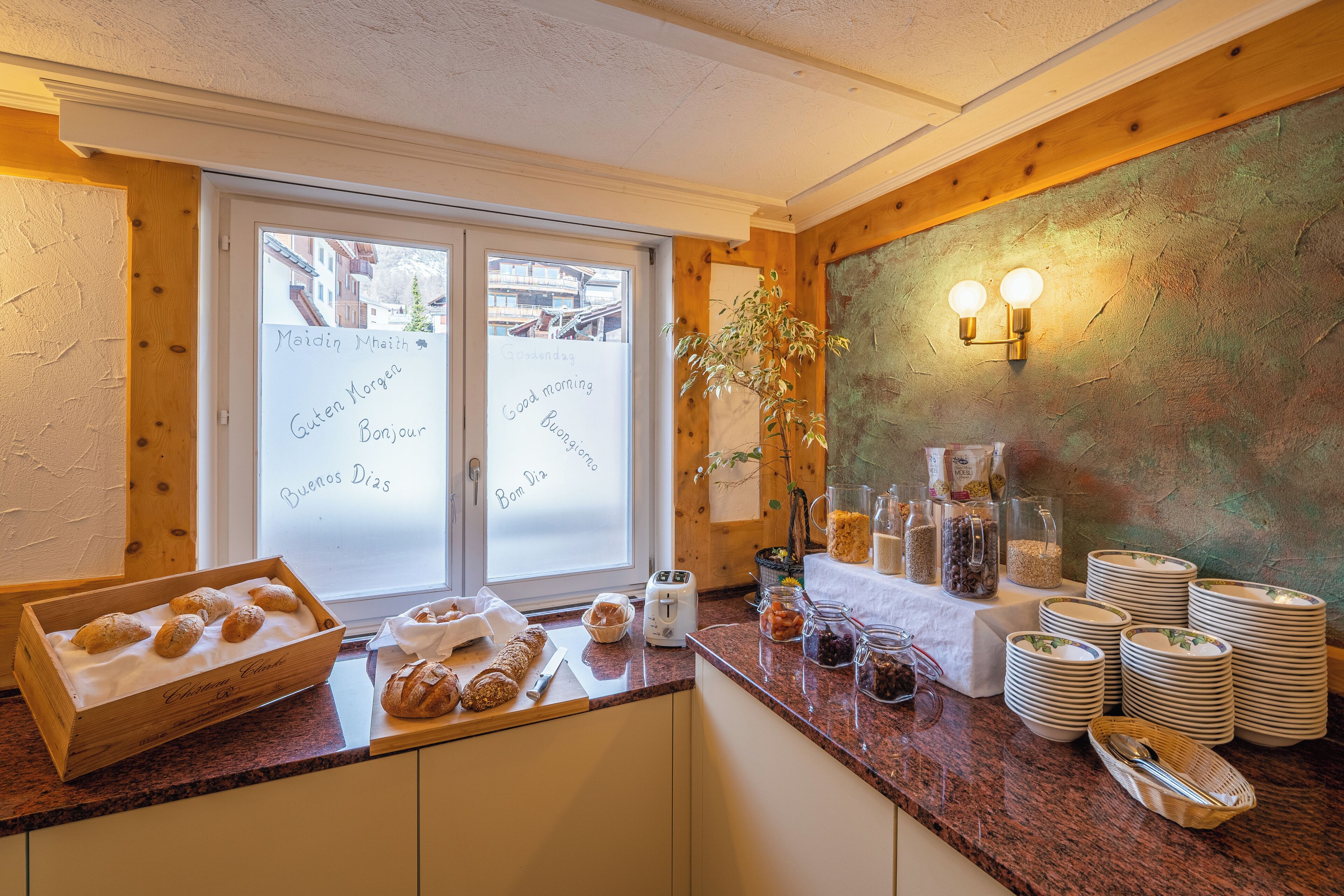 Una cocina con encimera de madera, panera, tostadora y ventana con vistas a edificios.