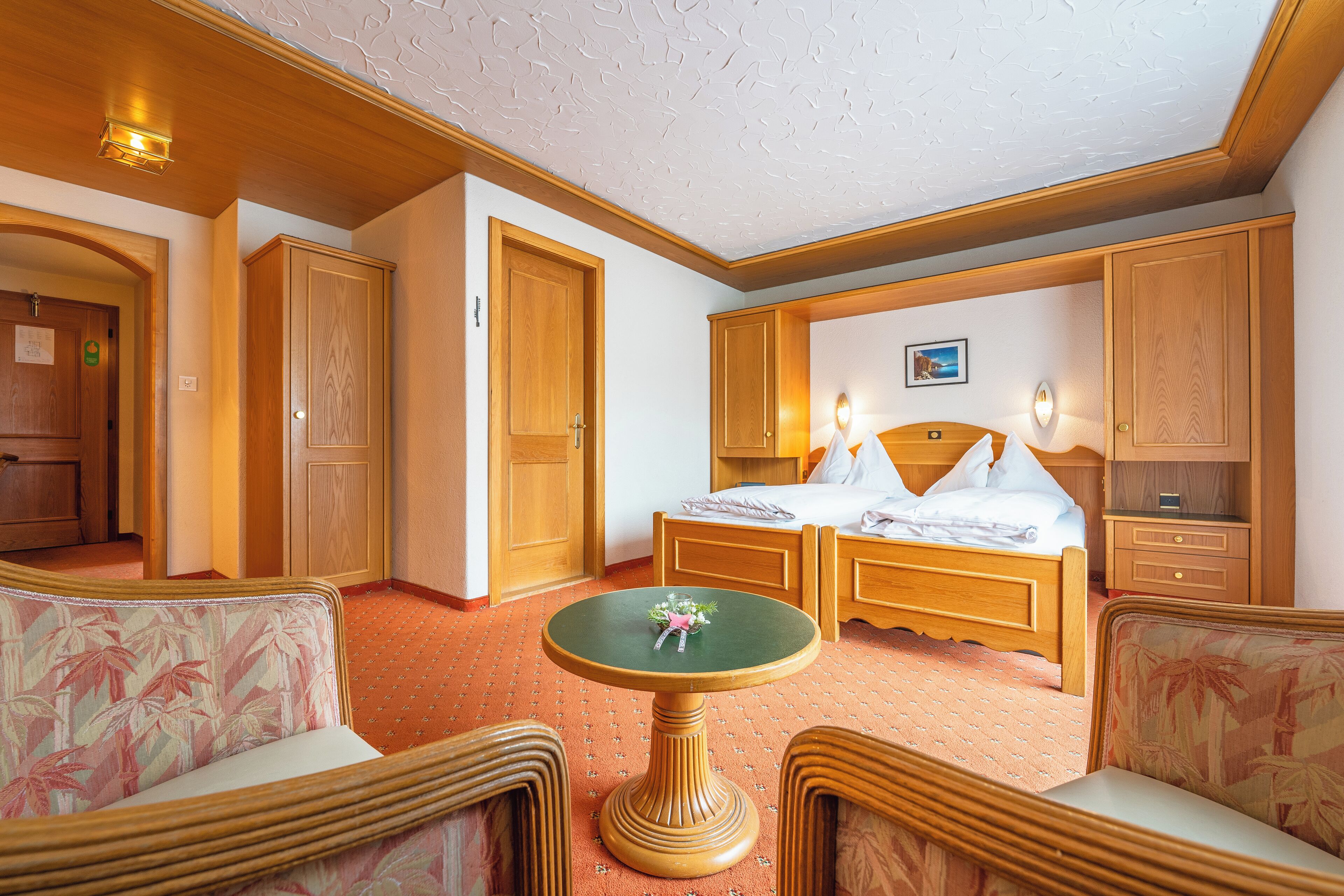 Ein Hotelzimmer mit einem Bett, zwei Nachttischen, einem kleinen runden Tisch und zwei Stühlen.