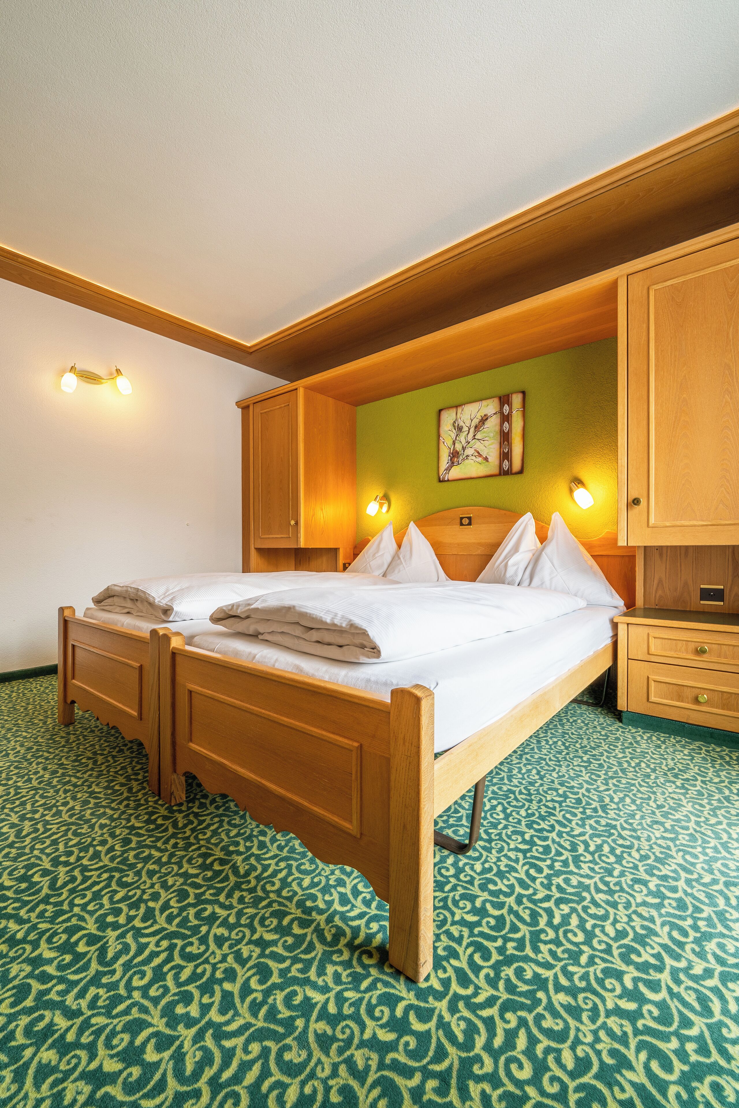 A neatly made bed with pillows and a blanket, wooden headboard, and bedside cabinets.