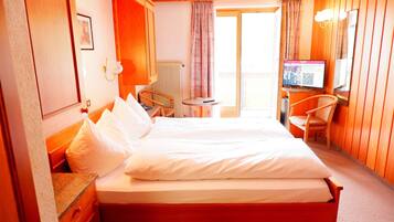 Hotelkamer met een groot bed, een bureau met stoel, een televisie en uitzicht op buiten.