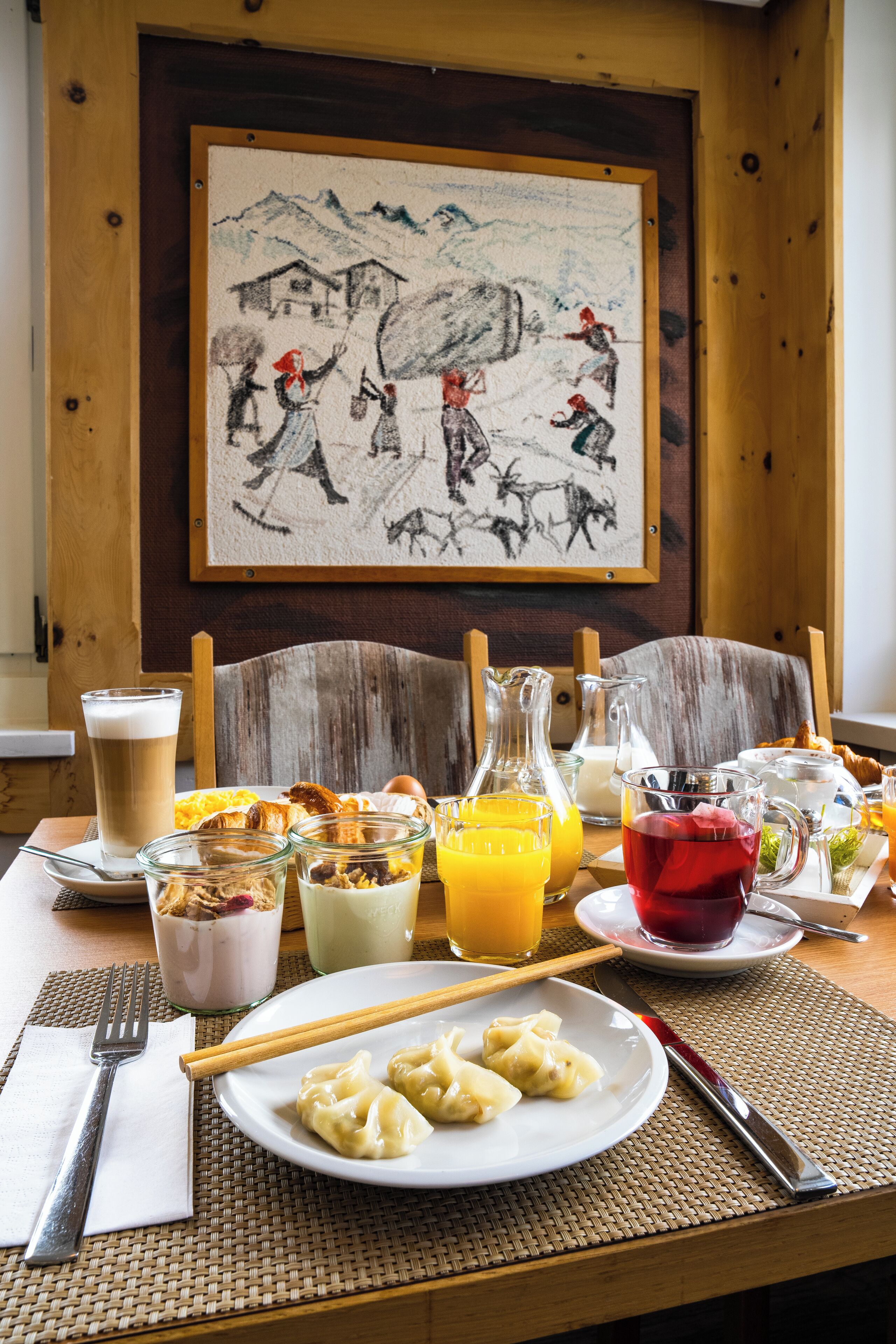 Una tavola imbandita con un pasto, tra cui gnocchi, bevande e un quadro appeso al muro.