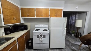 A compact kitchen with wooden cabinets, a white stove, and a refrigerator. - First floor 1Bed/1Bth Pets OK, Close to ProMedica, UT (Toledo)