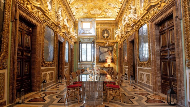 An opulent room with a large glass table, ornate gold detailing, and a grand chandelier. - Palazzo Shedir - The Leading Hotels of the World (Rome)