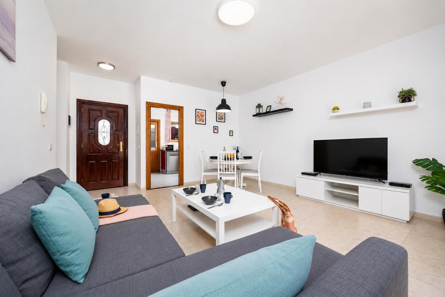 Un salon comprenant un canapé, une table basse, un téléviseur et un coin repas avec des chaises et une table.