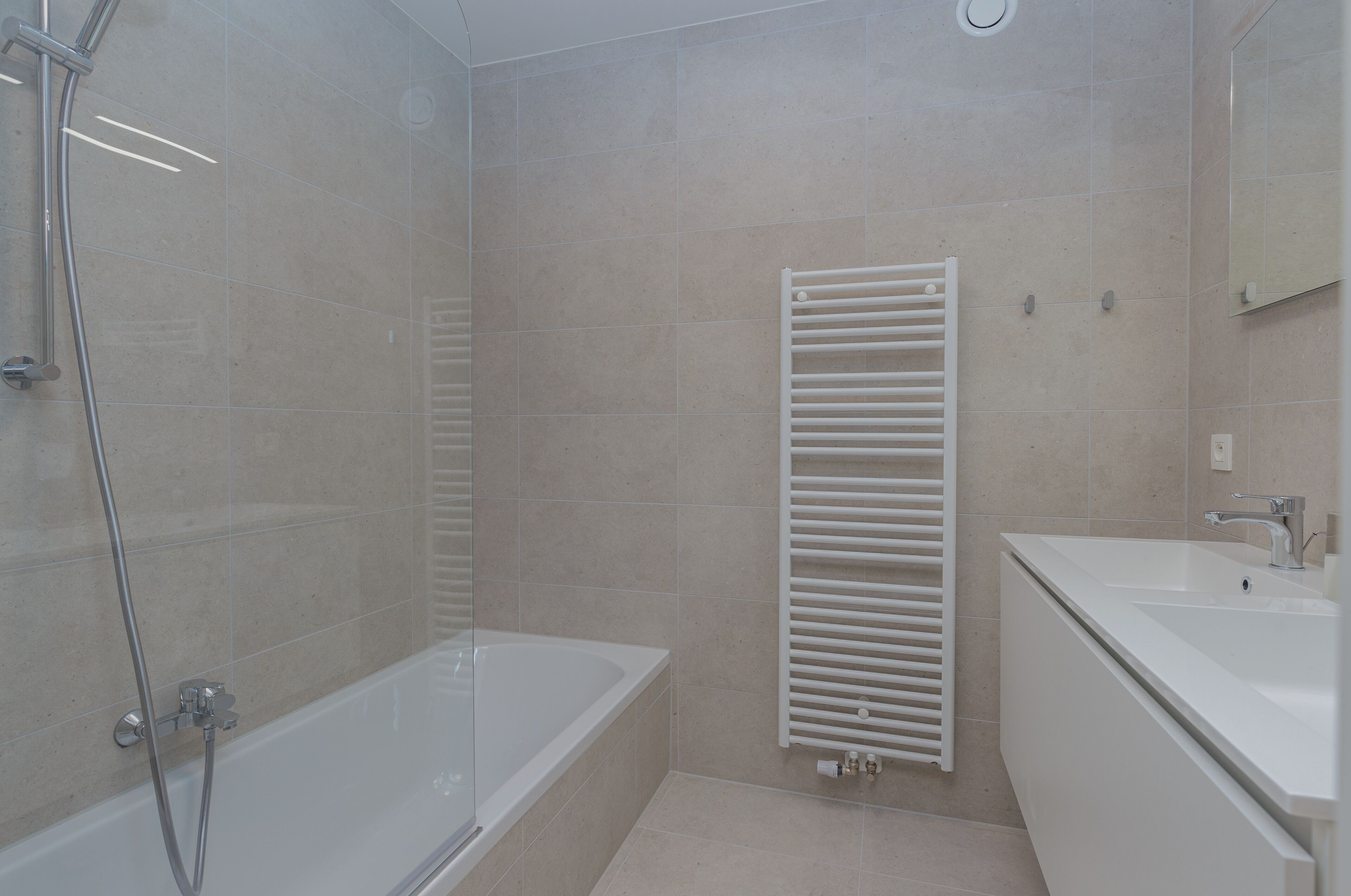 Een moderne badkamer met een bad, douche en wastafel.