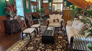 A traditional living room with a sofa, armchairs, a coffee table, and a staircase. - Woodbine Inn and Restaurant (Madisonville)