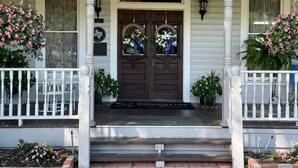 A porch with a double door, white railings, and a sign that reads "Goodwine". - Woodbine Inn and Restaurant (Madisonville)
