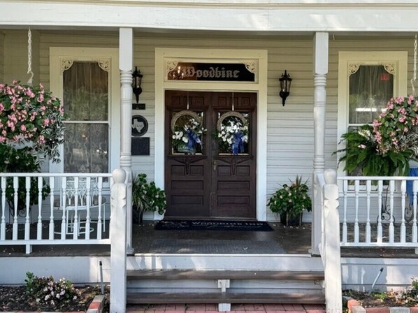 A porch with a double door, white railings, and a sign that reads "Goodwine". - Woodbine Inn and Restaurant (Madisonville)