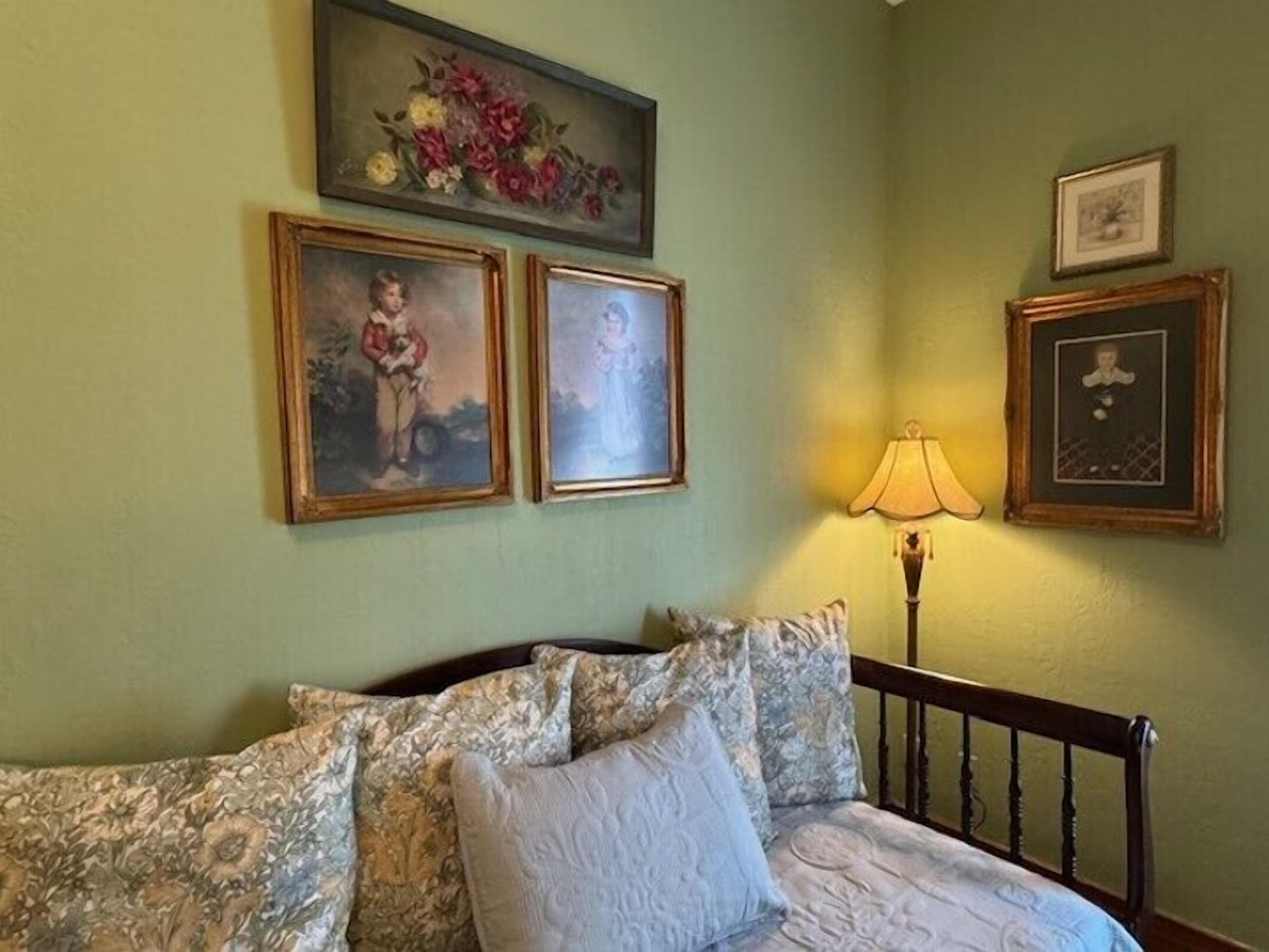 A bedroom with a bed, a lamp, and three framed pictures on the wall.