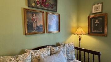 A bedroom with a bed, a lamp, and three framed pictures on the wall.