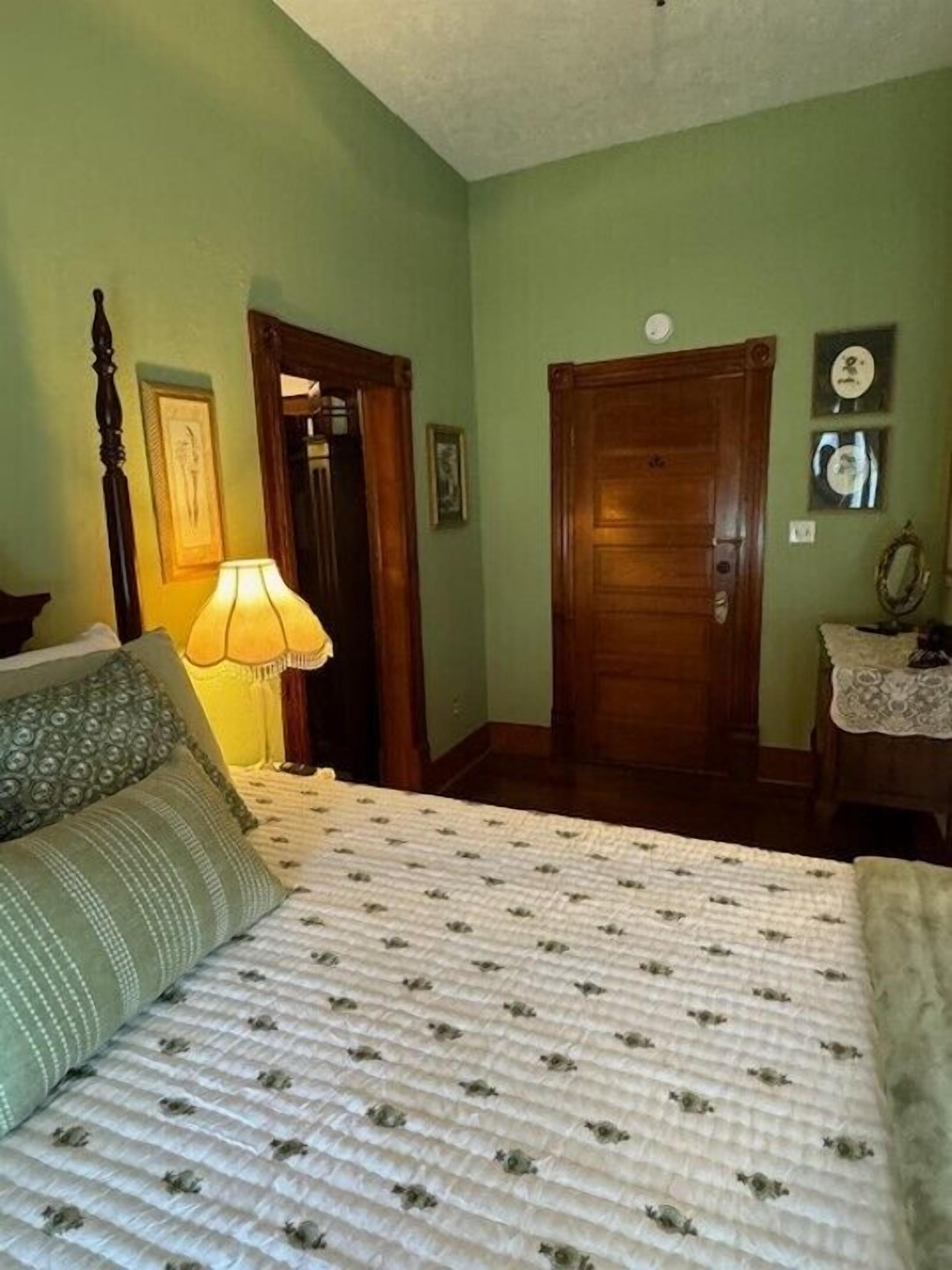 Ein Schlafzimmer mit Bett, Nachttisch, Lampe und Tür.