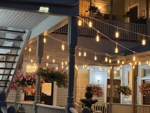 A covered outdoor area with string lights, wooden railings, and hanging flower arrangements. - Woodbine Inn and Restaurant (Madisonville)