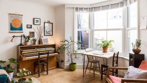 Una sala de estar acogedora con un piano, una mesa de comedor y varias plantas en macetas.