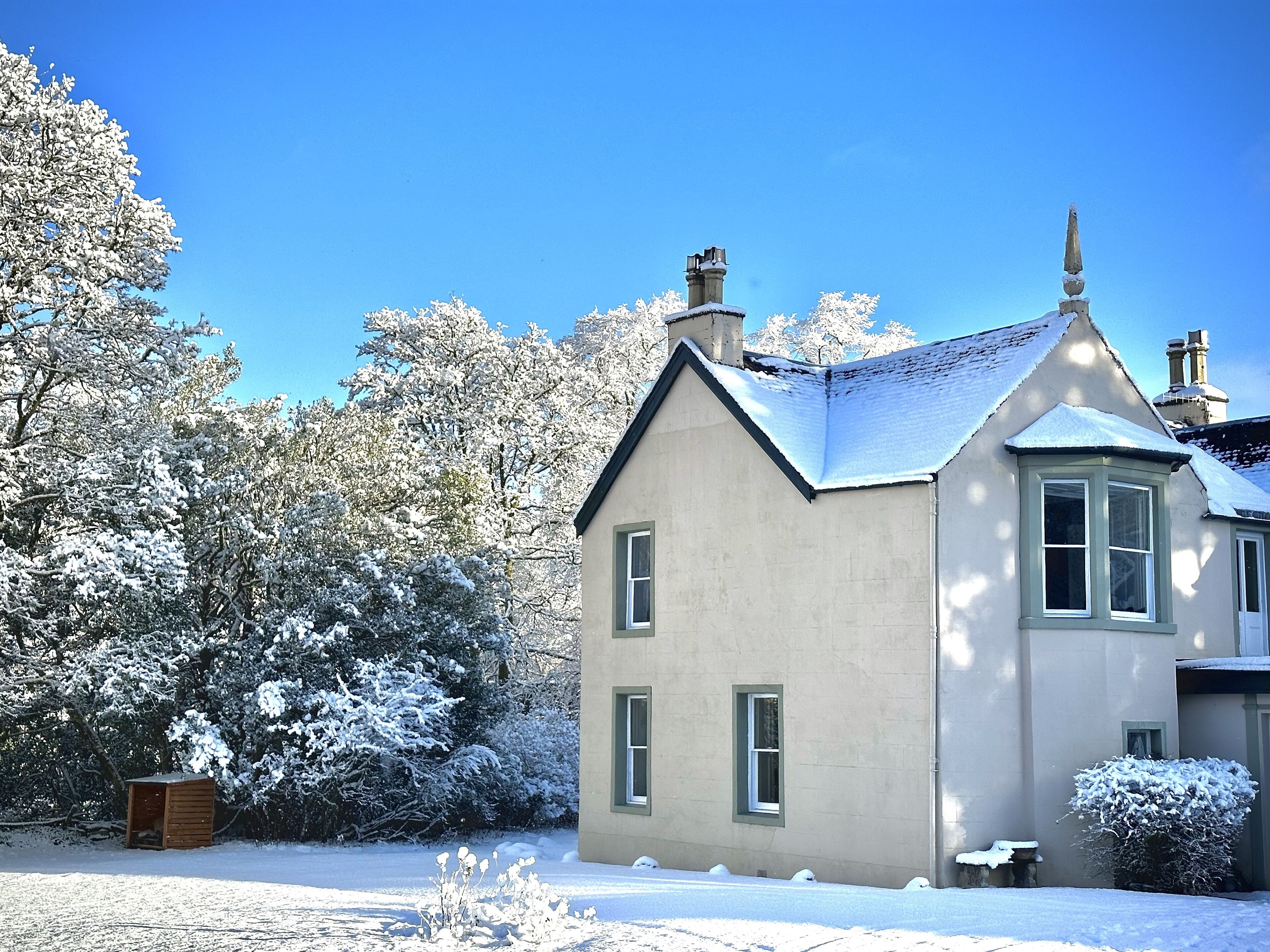 A two-story house with a snow-covered roof and a chimney.