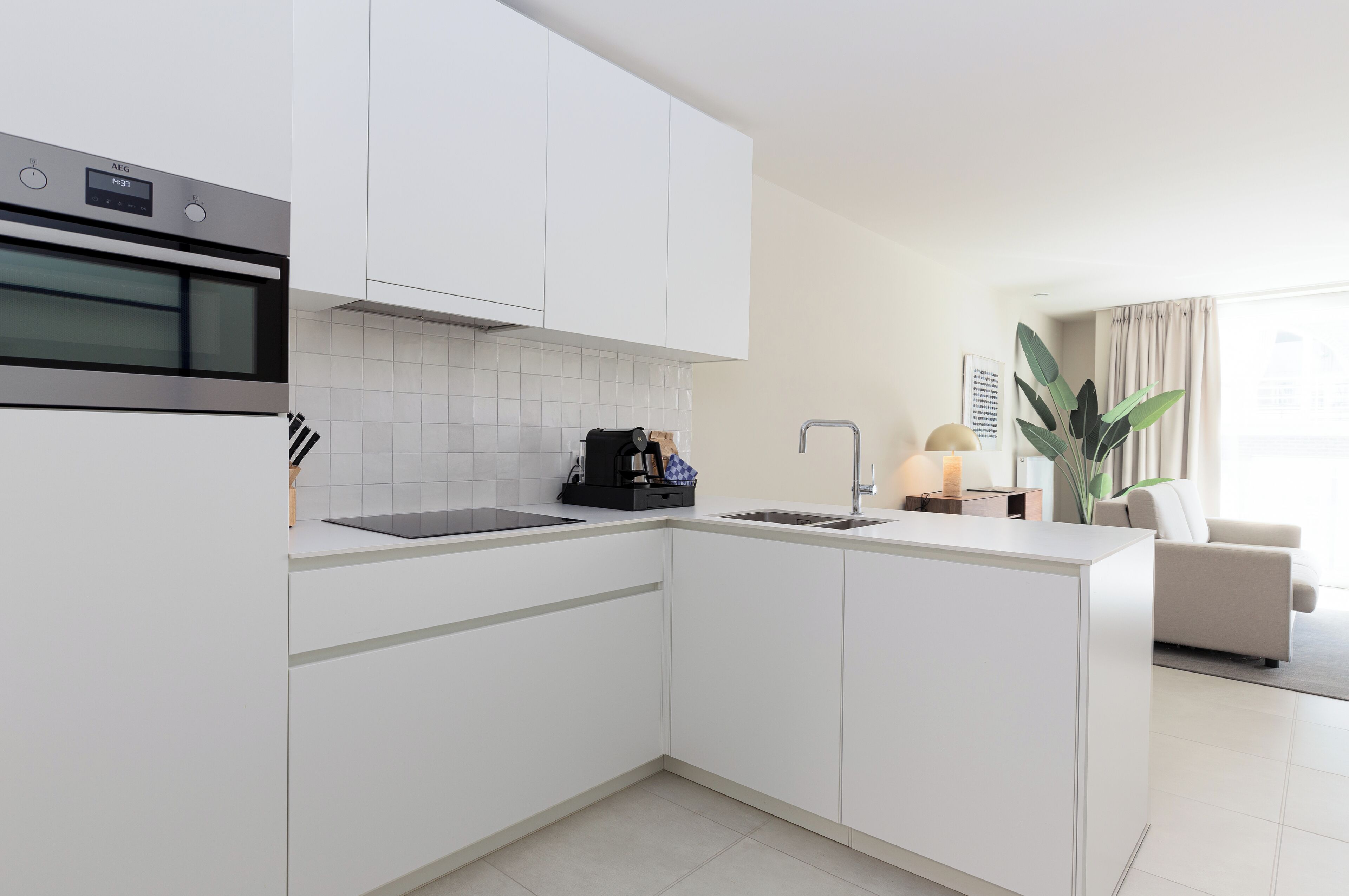 Una cocina moderna con armarios blancos, horno empotrado y un fregadero.