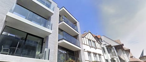 Un immeuble résidentiel à plusieurs étages, doté de balcons, de grandes fenêtres et surplombant un ciel dégagé.