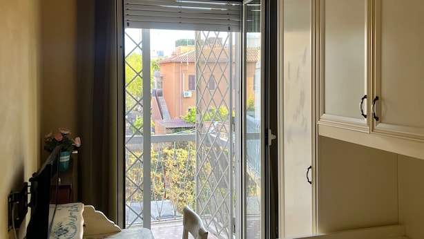 A room with a bed, a table with a chair, a small desk, and a window with curtains. - Specter Guesthouse (Nettuno)