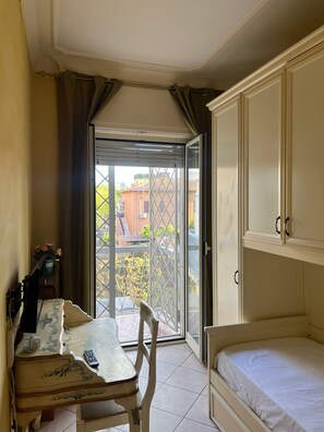 Una habitación con cama, una mesa con silla, un escritorio pequeño y una ventana con cortinas.