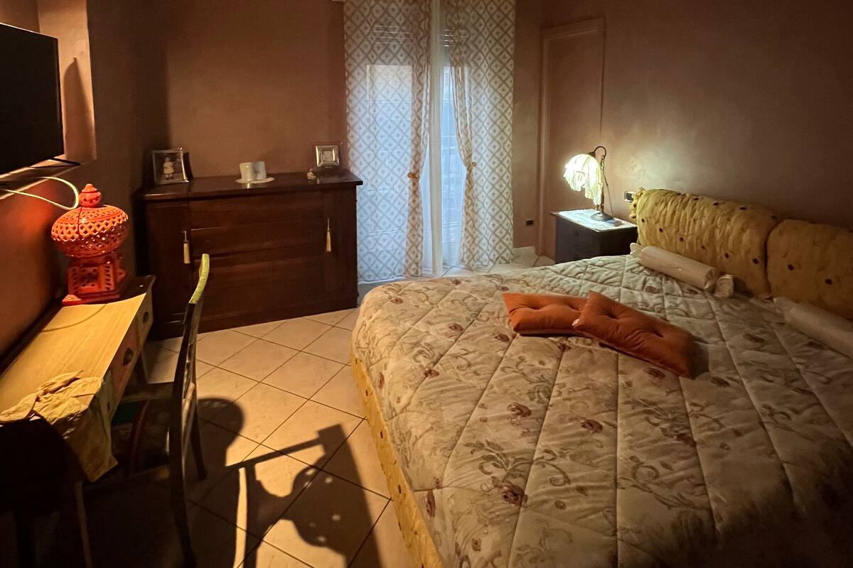 A bedroom with a bed, a desk, a chair, a wardrobe, and a television.