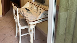 A small room with a table and a chair, a television, and a door leading to another room. - Specter Guesthouse (Nettuno)