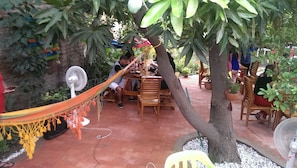 A patio area with wooden tables and chairs, a hammock, and potted plants.