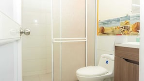 A bathroom with a white toilet, a glass shower enclosure, and a wooden vanity.