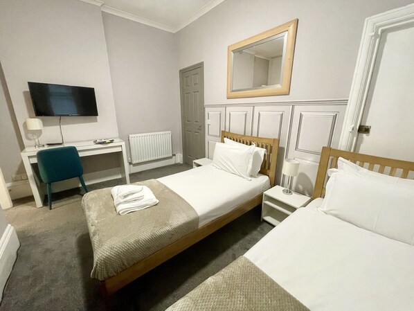 A hotel room with a bed, a desk, a chair, a television, and a mirror. - The X Hotel (Hove)