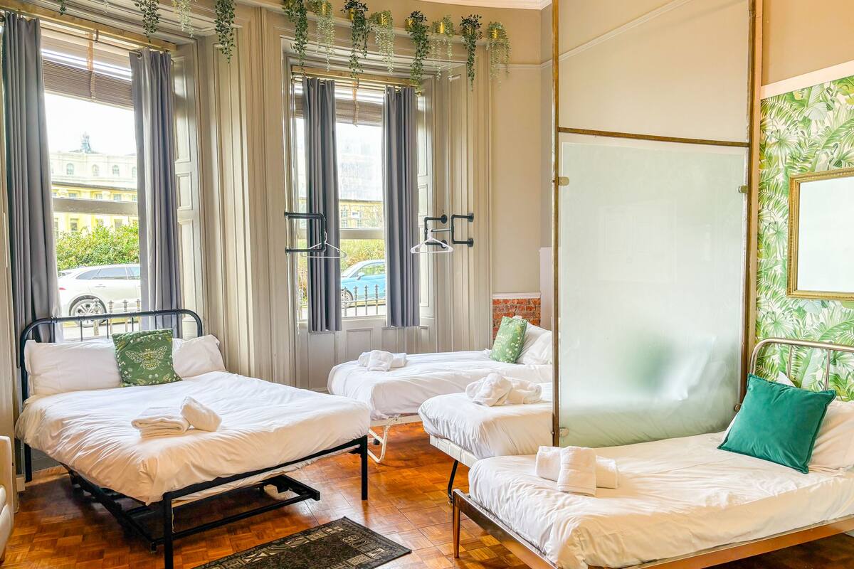 A hotel room with two beds, a view of the street, and a green patterned wall.
