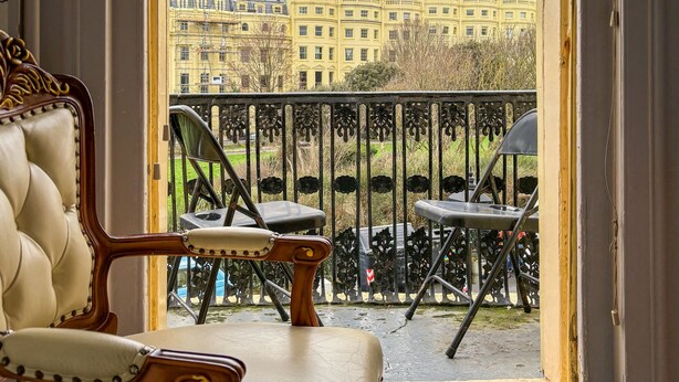 A room with a view of a yellow building through a window. There is a chair and a small table in the room. - The X Hotel (Hove)