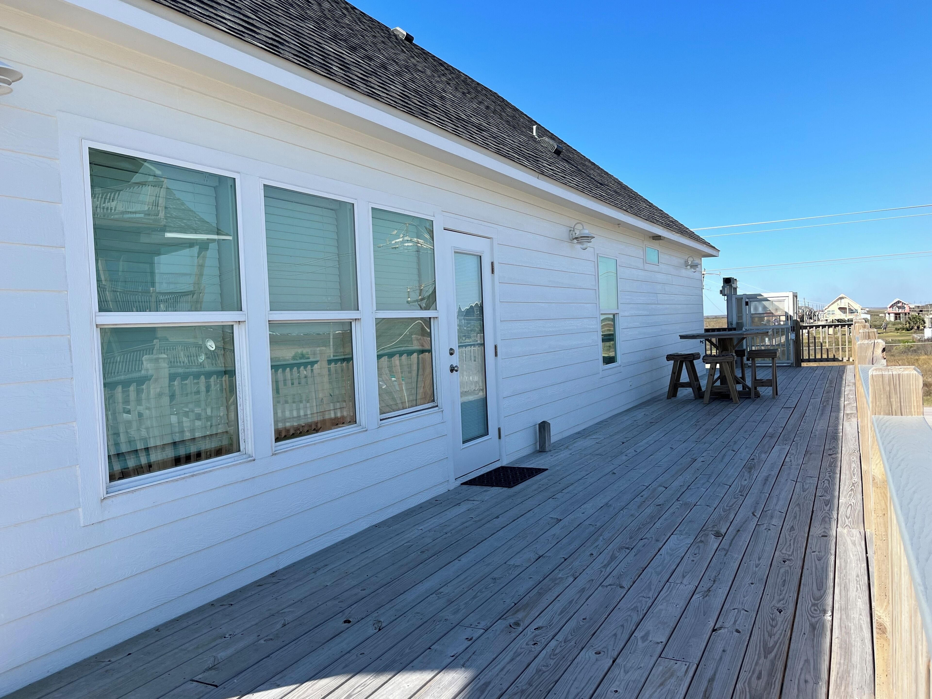 A white building with large windows and a wooden deck.