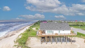 Een huis aan het strand met een houten terras en uitzicht op de oceaan.