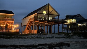 Een object aan het strand, met een hoofdgebouw voorzien van een groot balkon en een tweede huis met een terras.