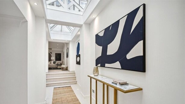 A modern hallway with a skylight, a console table with books, and a large abstract painting. - 4 bedroom home by Buckingham Palace (London)