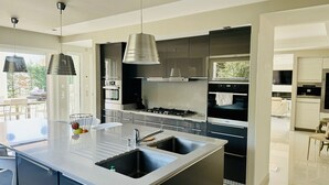 A modern kitchen with a central island, stainless steel appliances, and pendant lighting. - Villa Monte-christo - Propriété D'exception au Coeur de la Cote D'azur (Saint-Cézaire-sur-Siagne)