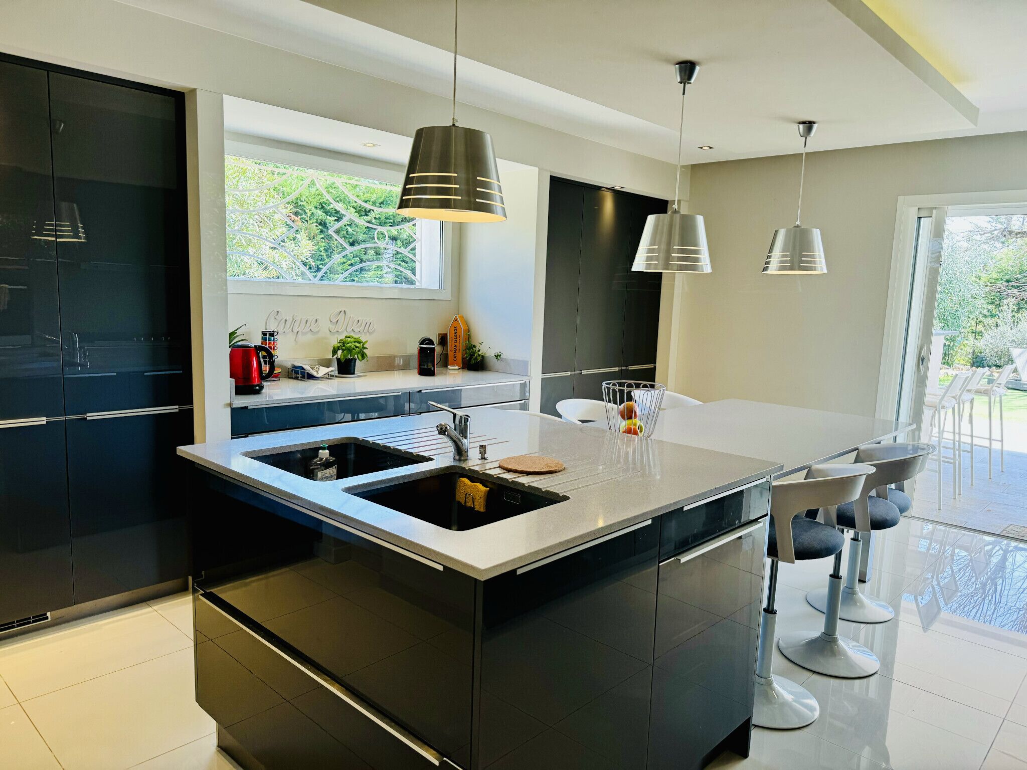 Una cocina moderna con una isla central, armarios negros e iluminación colgante.