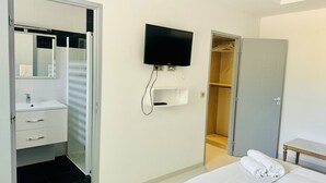 A hotel room with a bed, a television mounted on the wall, a wardrobe, and a bathroom with a mirror and sink. - Villa Monte-christo - Propriété D'exception au Coeur de la Cote D'azur (Saint-Cézaire-sur-Siagne)